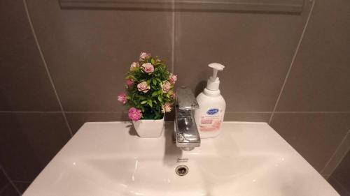 - un lavabo avec une bouteille de savon et des fleurs dans l'établissement Lacasita condo convenient 1, à Hua Hin