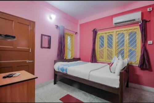 a bedroom with a bed with pink walls and a door at The Orchid Inn in Kolkata