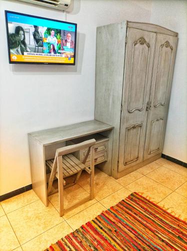 a tv on a wall with a desk and a cabinet at Hostal Restaurante Solaire in Castañar de Ibor