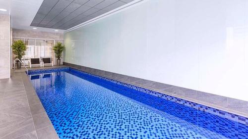 uma grande piscina com água azul num quarto em CBD Penthouse View Apartment em Adelaide