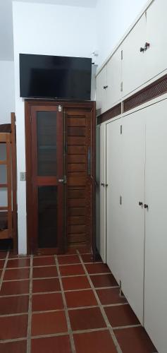 a kitchen with white cabinets and a brown tile floor at Royal-inn SPA & Pousada in Itanhaém