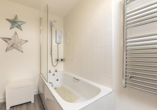 a white bathroom with a tub and a toilet at 2B Pen Y Bont in Abersoch