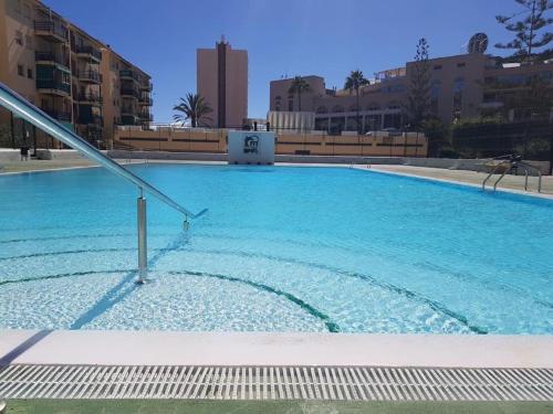 uma grande piscina azul com edifícios ao fundo em Sun Apartment Cristimar (3 bedrooms) em Los Cristianos