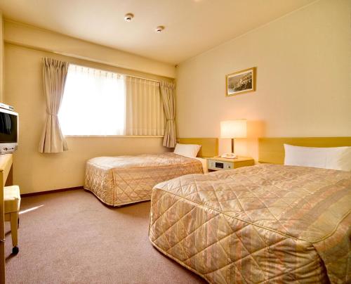 a hotel room with two beds and a window at Kurashiki Ekimae Universal Hotel in Kurashiki