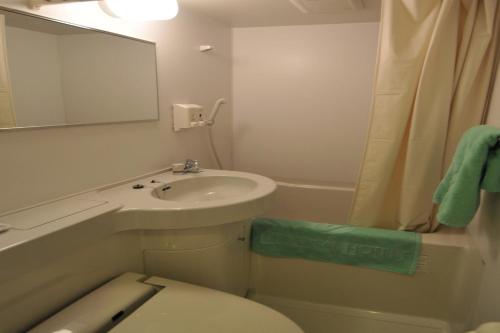 La salle de bains est pourvue d'un lavabo, de toilettes et d'un miroir. dans l'établissement Kurashiki Ekimae Universal Hotel, à Kurashiki