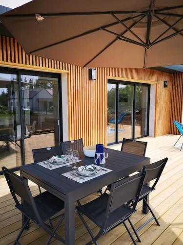 une table noire et des chaises sur une terrasse dans l'établissement Maison Penmarc'h 800 m plage, 10 mn La Torche, à Penmarcʼh