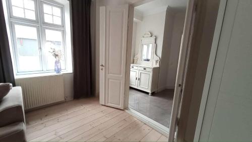 Habitación con espejo, tocador y ventana en Apartment in Danmark -Petersminde Exclusive Apartments, en Otterup