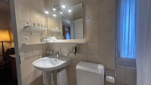 a bathroom with a sink and a toilet and a mirror at Hotel Du Lac in Interlaken