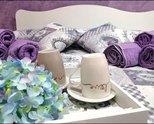 a bed with pillows and two cups and a flower at Le tre cime in Baranello