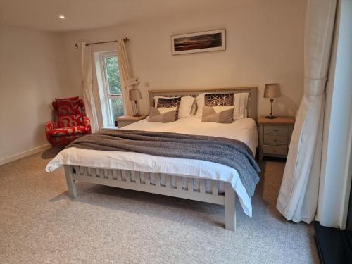 a bedroom with a large bed and a red chair at Treworgie Barton - Warner in Bude