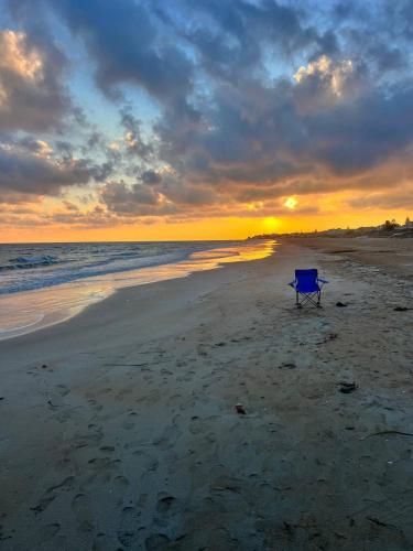 a blue chair sitting on the beach at sunset at Mare Nostrum TF in Tre Fontane