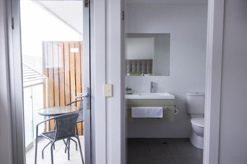 La salle de bains est pourvue d'un lavabo, de toilettes et d'une table. dans l'établissement The Apollo, à Apollo Bay