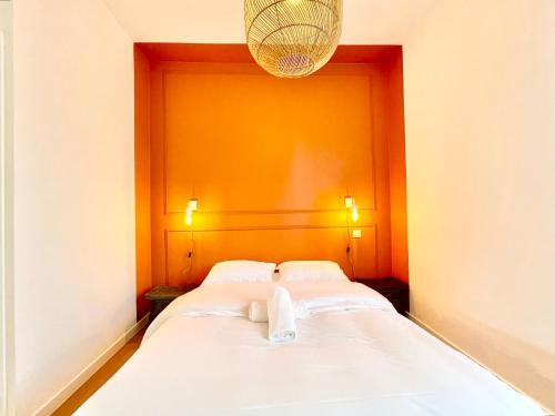 een bed in een kamer met een oranje muur bij Le Maine, Proche Gare in Saint-Nazaire