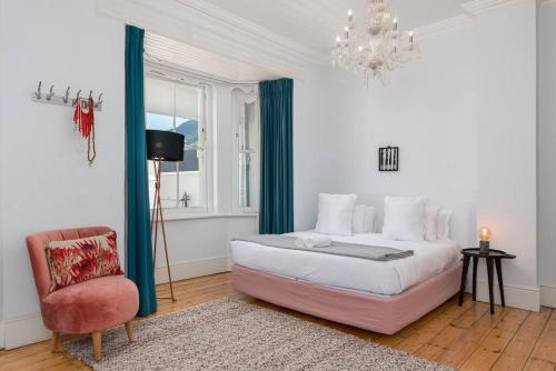 a bedroom with a bed and a chair and a chandelier at Victorian Townhouse with Table Mountain Views in Cape Town