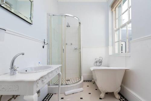a white bathroom with a tub and a sink at Victorian Townhouse with Table Mountain Views in Cape Town