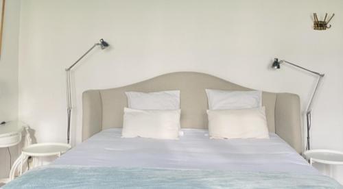 1 cama con sábanas blancas y almohadas blancas en Kasteelhof van Loppem, en Loppem