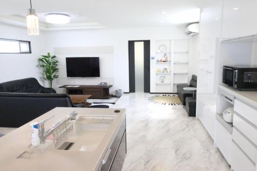 a white living room with a couch and a tv at Condominium Felicita Naha in Naha