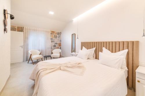 a bedroom with a large white bed with white pillows at Nono Ban Hotel & Villa in Gornji Humac