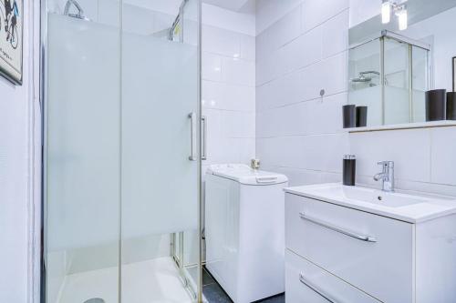 une salle de bain blanche avec un lavabo et une douche dans l'établissement Apartment 4Pers - Montparnasse/St Germain, à Paris