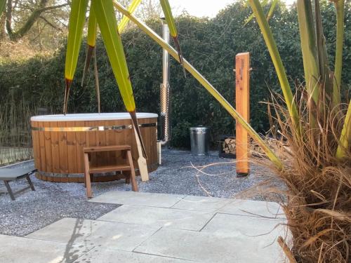 a wooden tub and a bench in a yard at Luxe 4- persoons Veluwelodge met hottub in Ermelo! in Ermelo