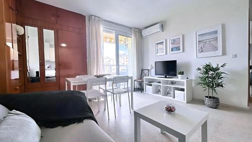 ein Wohnzimmer mit einem Sofa, Tischen und einem TV in der Unterkunft Zuhayra Beach Apartamento con Vista a 50m del Mar in Torrox Costa