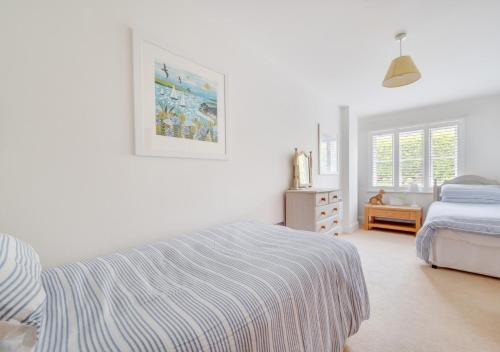 a white bedroom with a bed and a dresser at Pengliddon No.5 in Wadebridge