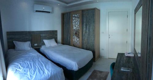 a bedroom with two beds and a table and a desk at فنادير in Hurghada