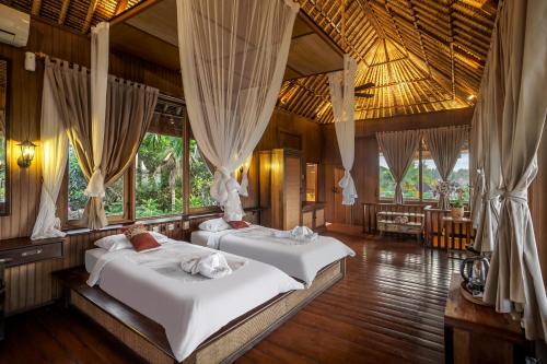Duas camas num quarto com janelas em Villa Sujati em Ubud