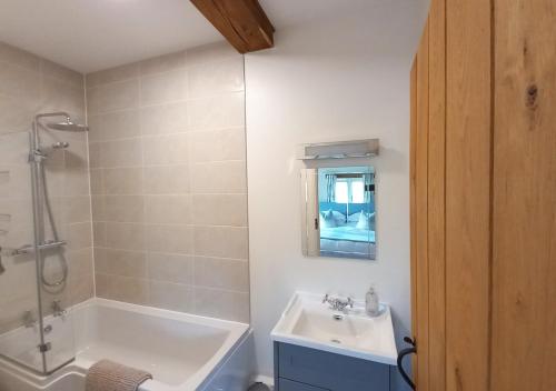 a bathroom with a tub and a sink and a shower at Barton Barn in Bishops Nympton