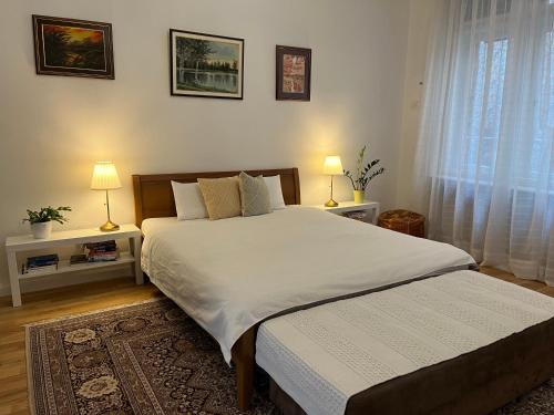 a bedroom with a bed and two lamps and a window at The Best Location salon apartment with main street view in Sarajevo