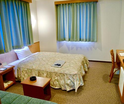 米子市にある米子ユニバーサルホテルのベッドとテーブルが備わるホテルルームです。