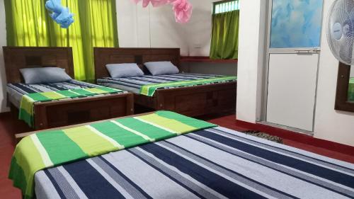 - 2 lits dans une chambre de couleur verte et bleue dans l'établissement Sewana Guest INN, à Wellawaya
