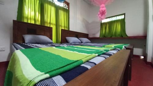 two beds in a room with green curtains at Sewana Guest INN in Wellawaya