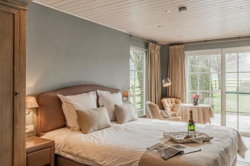 een slaapkamer met een bed en een tafel met een fles wijn bij B&B De Bergvallei in Oedelem