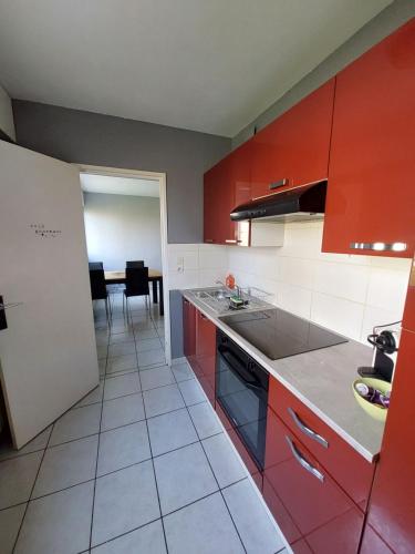 une cuisine avec des placards rouges et blancs et une table dans l'établissement L'appart d'Eugénie société selogerametz com, à Metz