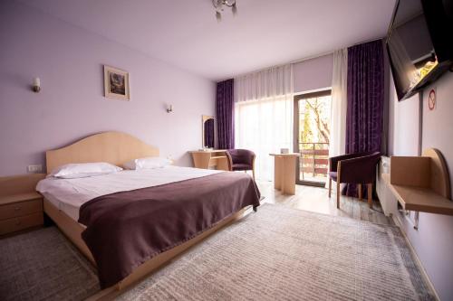 a bedroom with a bed and a large window at Pensiunea Andy in Braşov