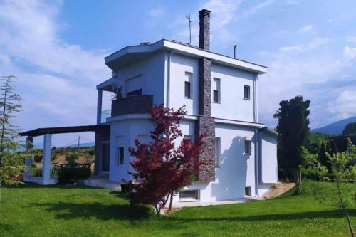 a white house with a chimney on a green field at Zeusplace Olympous Riviera Villa 1 in Litochoro