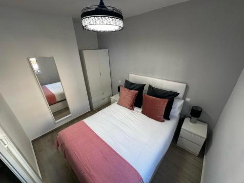 1 dormitorio con 1 cama con manta rosa y espejo en Market Martinez de la Riva IV en Madrid