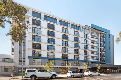 a large white building with cars parked in front of it at Castle Rock Apartment in Cape Town