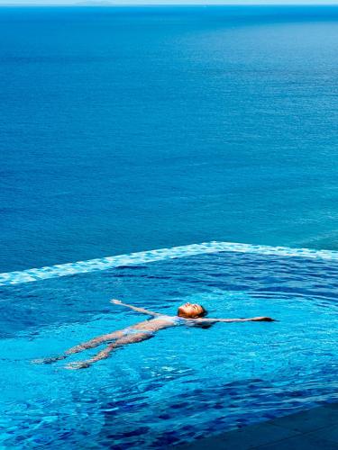 a person swimming in the water in the ocean at Villa Club Tropicana Carana with infinity pool in Machabee