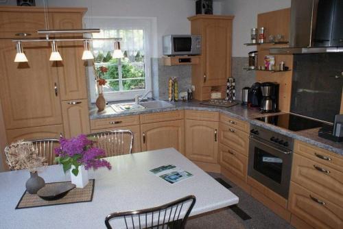 a kitchen with wooden cabinets and a table with purple flowers at Beckerhof - ABC54 in Dorf Mecklenburg