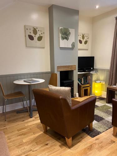 a living room with a couch and a table and a tv at Daffodil Cottage in Cockermouth