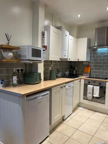 a kitchen with white cabinets and white appliances at Daffodil Cottage in Cockermouth