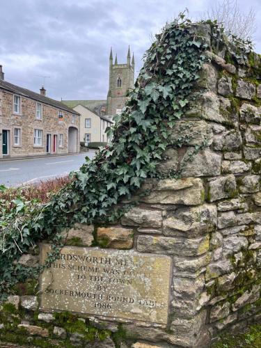 a stone wall with green ivy growing on it at Daffodil Cottage in Cockermouth