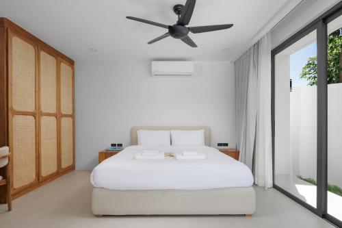 a bedroom with a white bed with a ceiling fan at The Villa Coco in Koh Samui 
