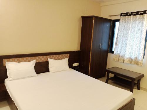 1 dormitorio pequeño con 1 cama y armario en Hotel Sharayu, en Sonai