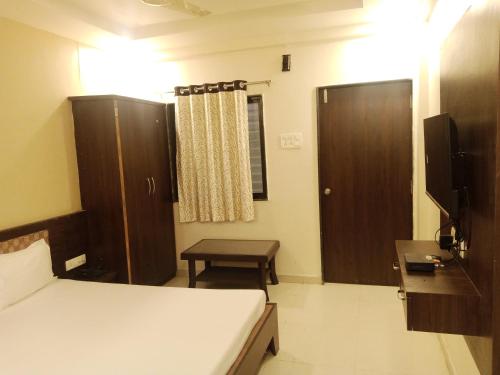 Dormitorio con cama, escritorio y TV en Hotel Sharayu, en Sonai