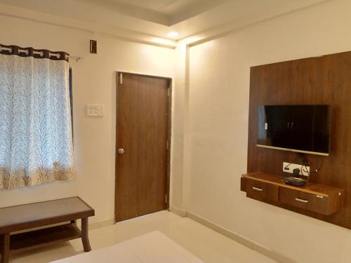 sala de estar con TV y puerta de madera en Hotel Sharayu, en Sonai