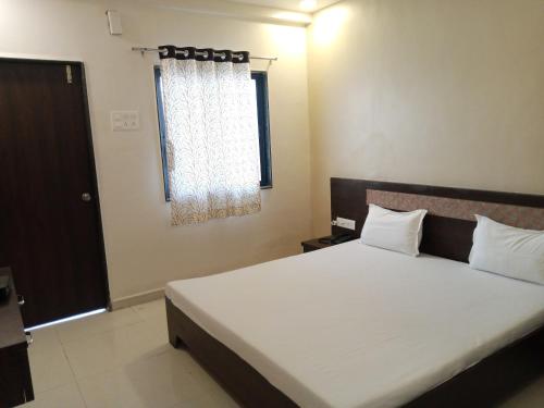 1 dormitorio con 1 cama blanca grande y ventana en Hotel Sharayu, en Sonai