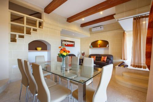 a dining room with a glass table and white chairs at Carini Farmhouses in Għarb